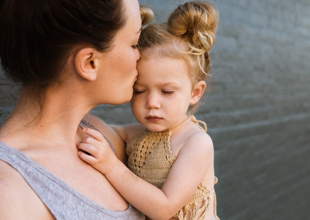Mother kissing her toddler, showcasing a nurturing bond, reflecting the supportive environment of Luv-N-Care Learning Center's toddler program focused on emotional growth and connection.